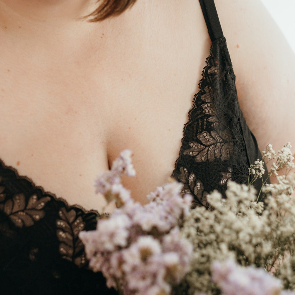 Une femme tient des fleurs à la main et porte des sous-vêtements en dentelle noire