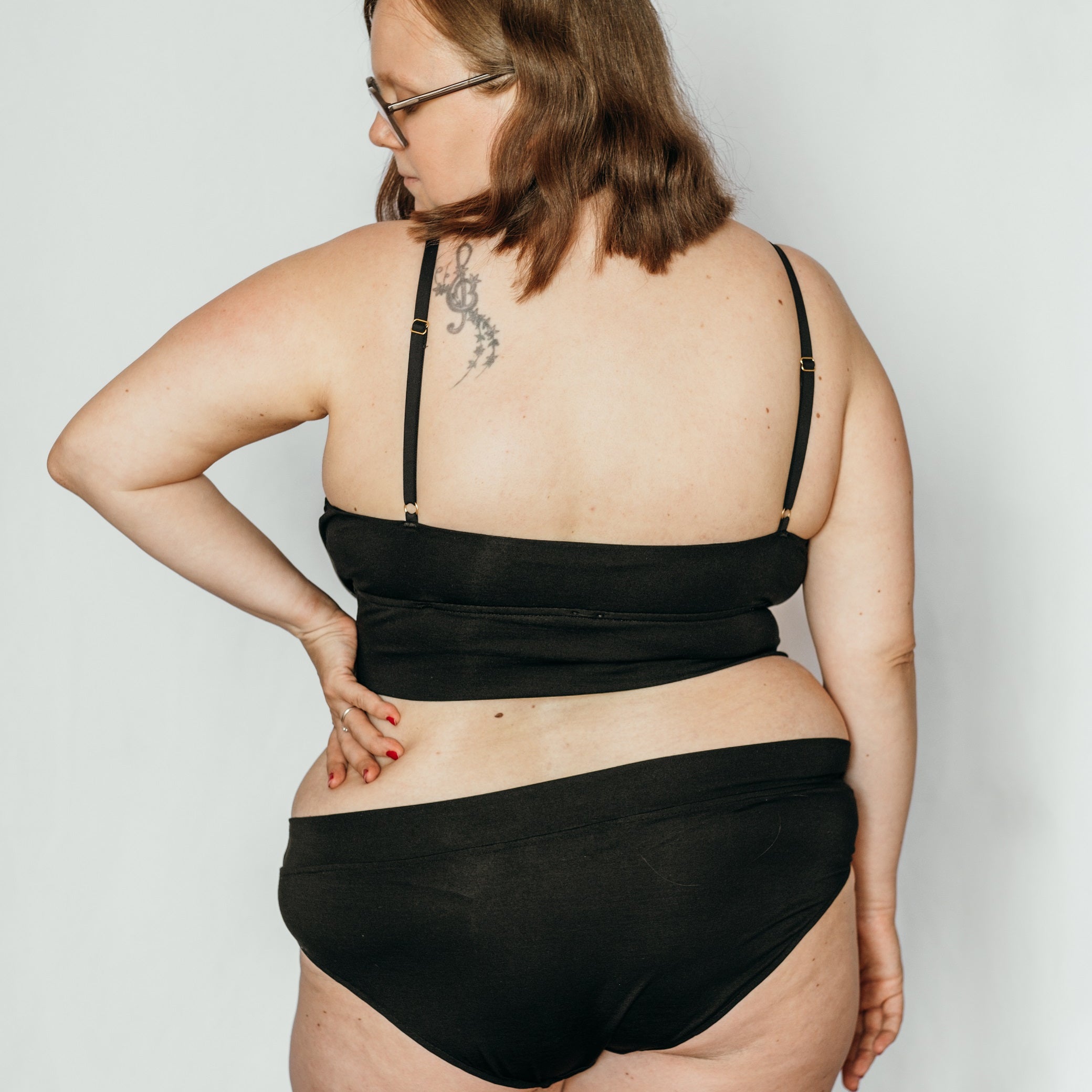 Le modèle porte Slip et Bandeau Bralette en TENCEL™ et avec des détails dorés