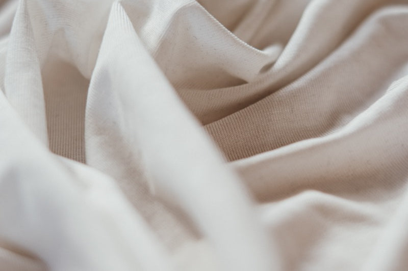 Photo shows yardage of white Tencel fabric. The fabric was lightly puffed together with hands and looks cozy.