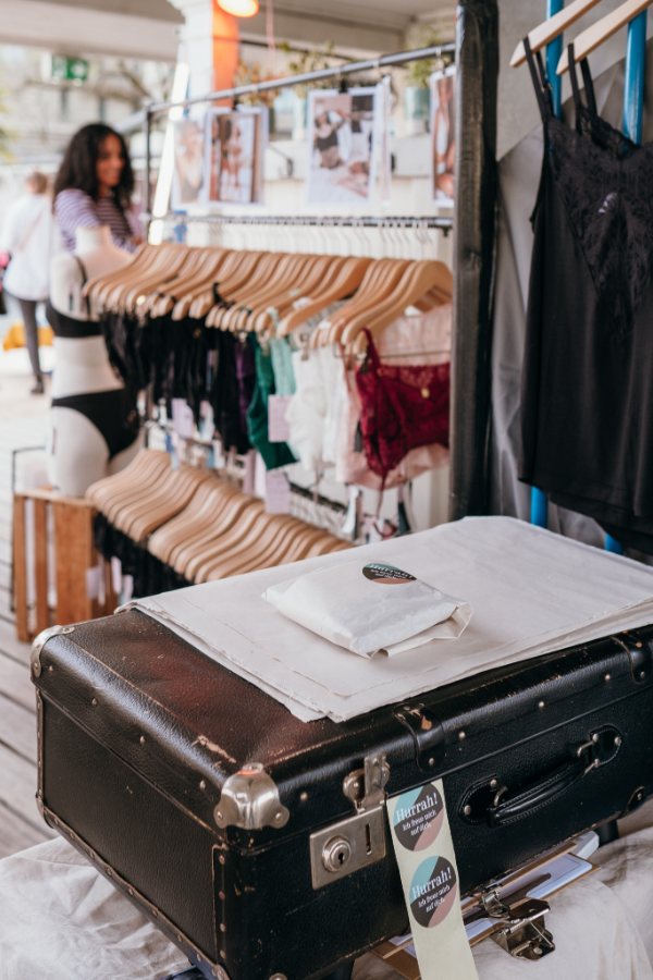 Package of thoughts of september lies on a suitcase at the fair, behind it a clothes rail with underwear.