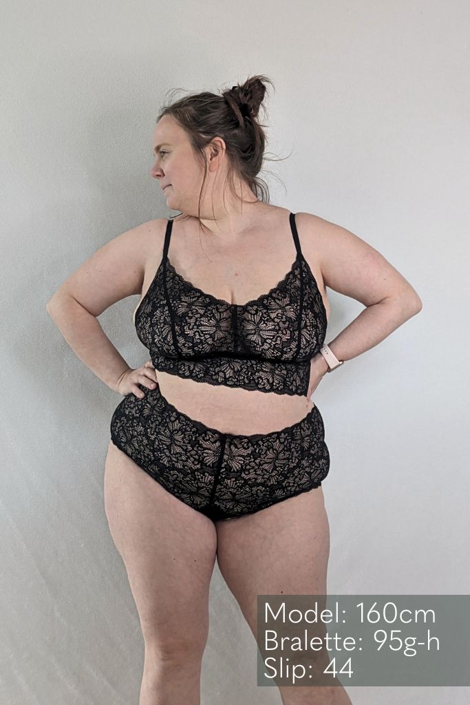 The woman looks to the side and poses in a large size the beautiful lacy underwear