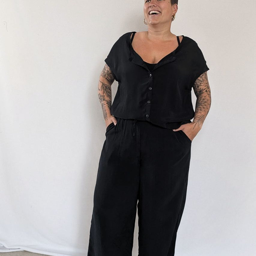 the smiling model poses in the Noe top with buttons and the Coco culottes in black