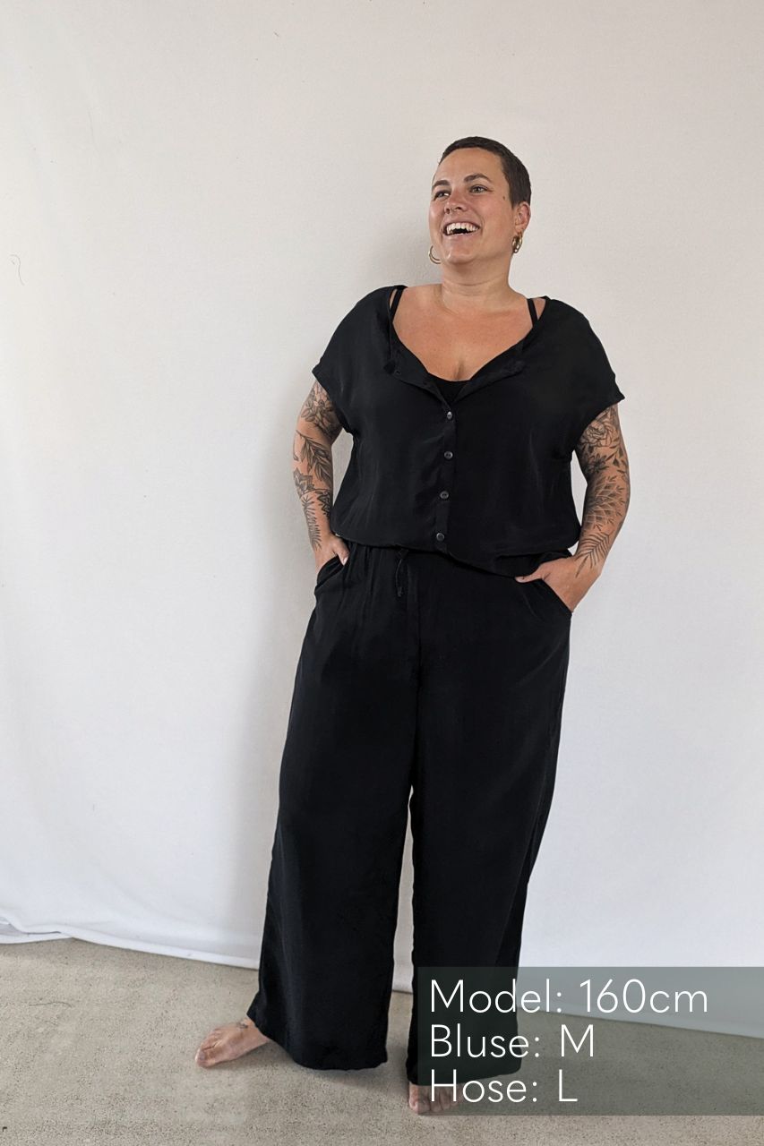 the smiling model poses in the Noe top with buttons and the Coco culottes in black