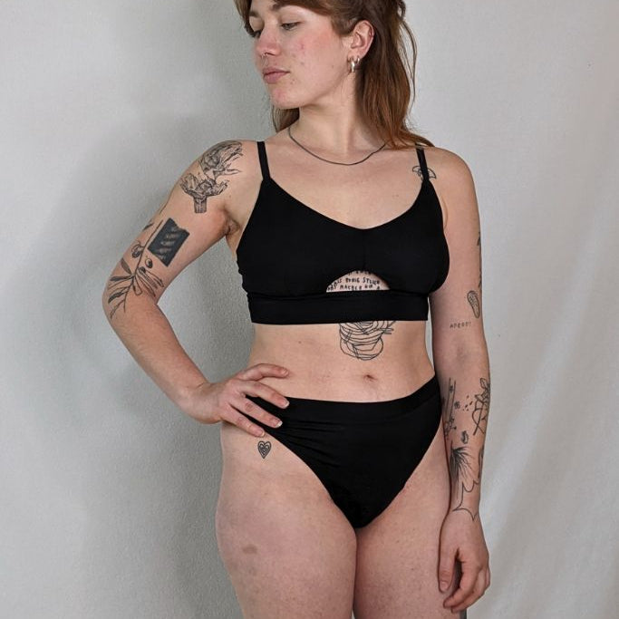 die tattoowierte Frau posiert im Thea String und Thea Bralette mit einem sexy cut out vorne