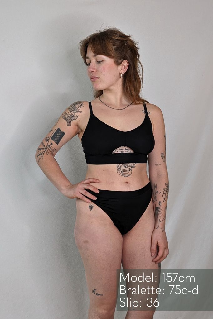 die tattoowierte Frau posiert im Thea String und Thea Bralette mit einem sexy cut out vorne