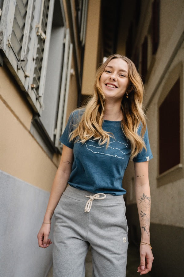 eine lachende Frau läuft durch die Gasse mit T-Shirt und Hose