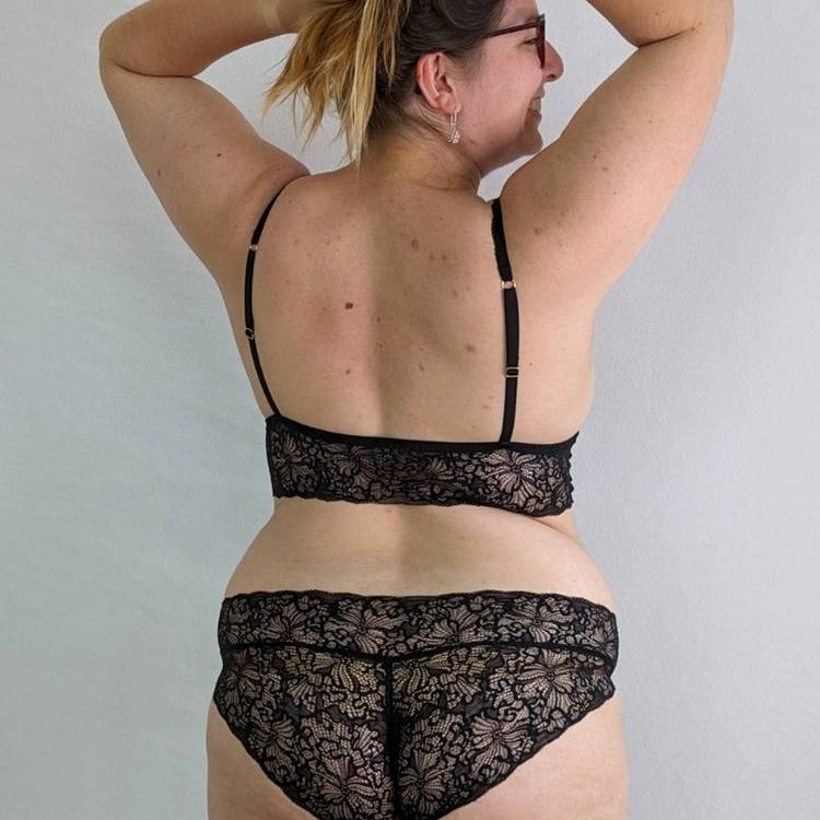 Person in Bralette and slip holding their hair up.