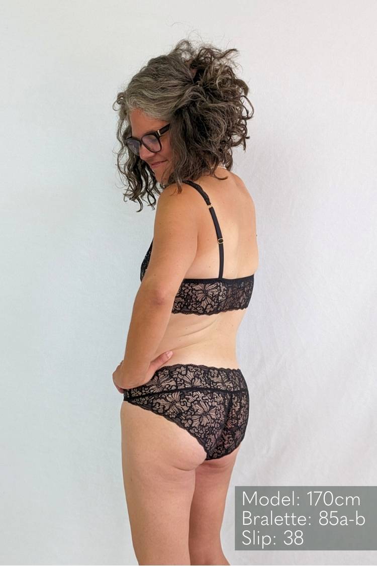Person in black lace lingerie looks over her shoulder.