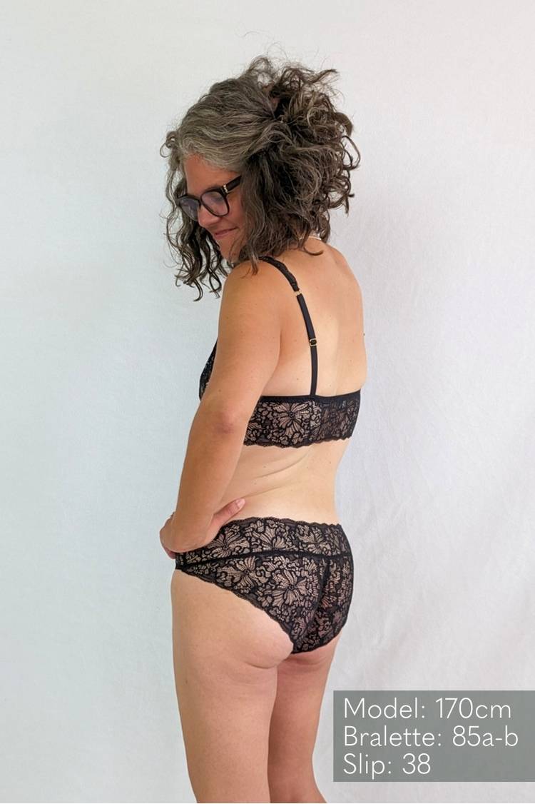 Une personne en lingerie noire en dentelle regarde par-dessus son épaule.