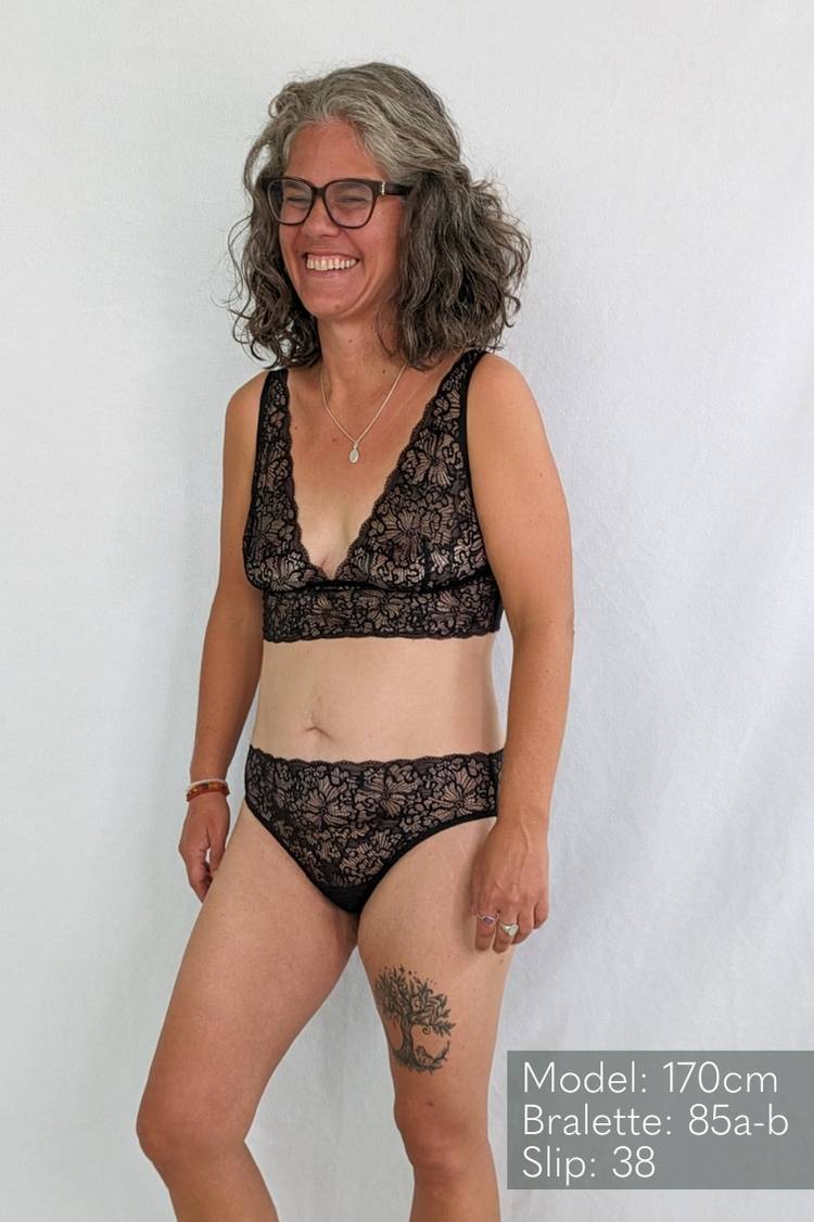 Woman in bra and slip made of lace smiles happily.