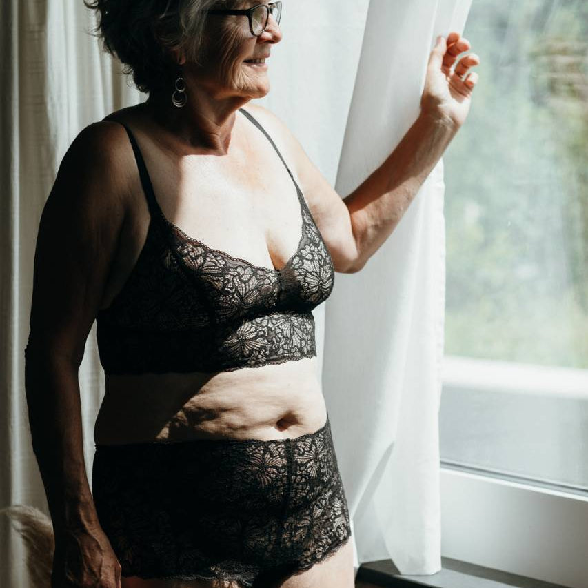 Model in a black set made of recycled lace looks out of the window.