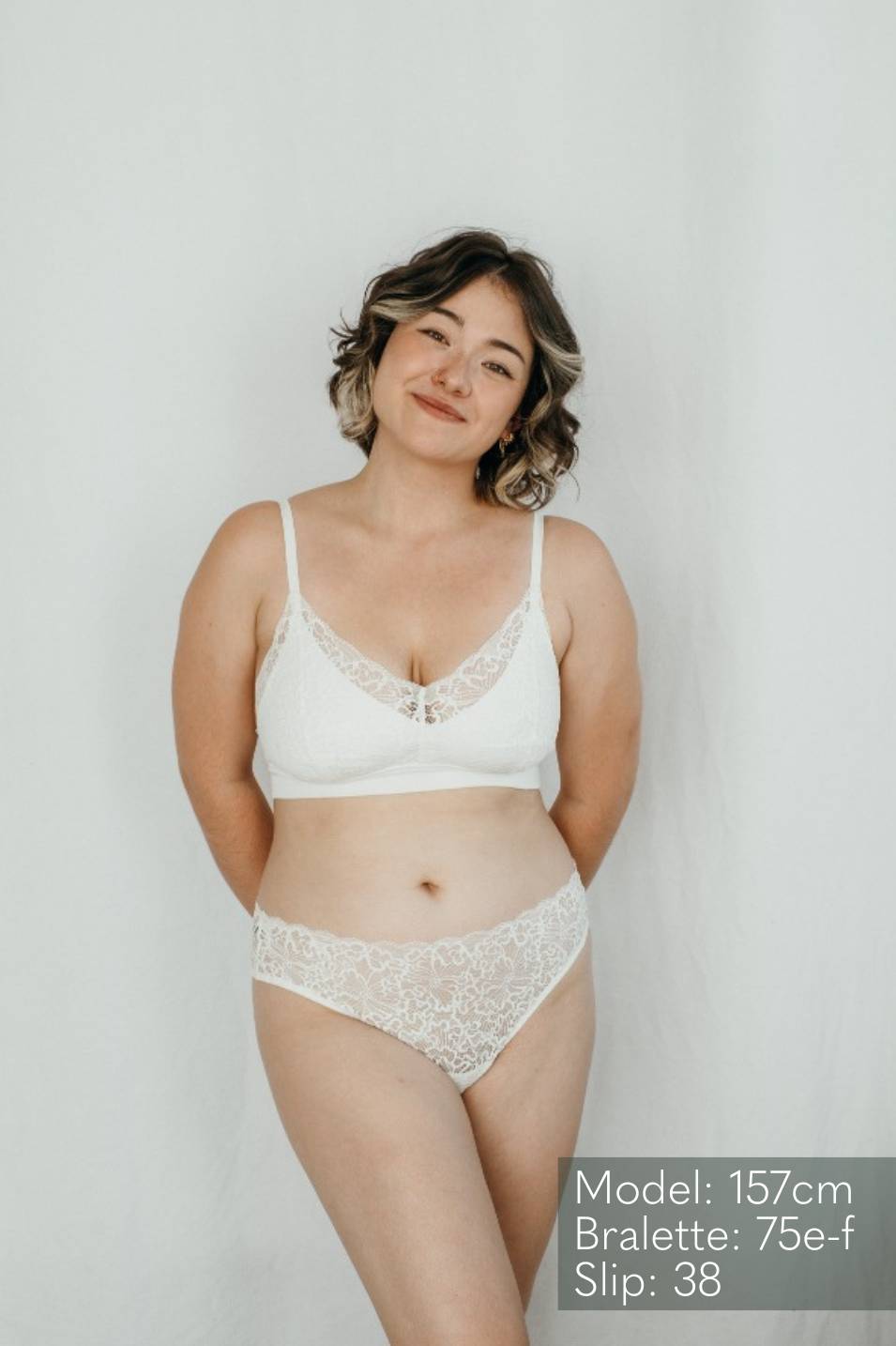 Model wears Bralette Lana and the matching String in ivory and smiles. 