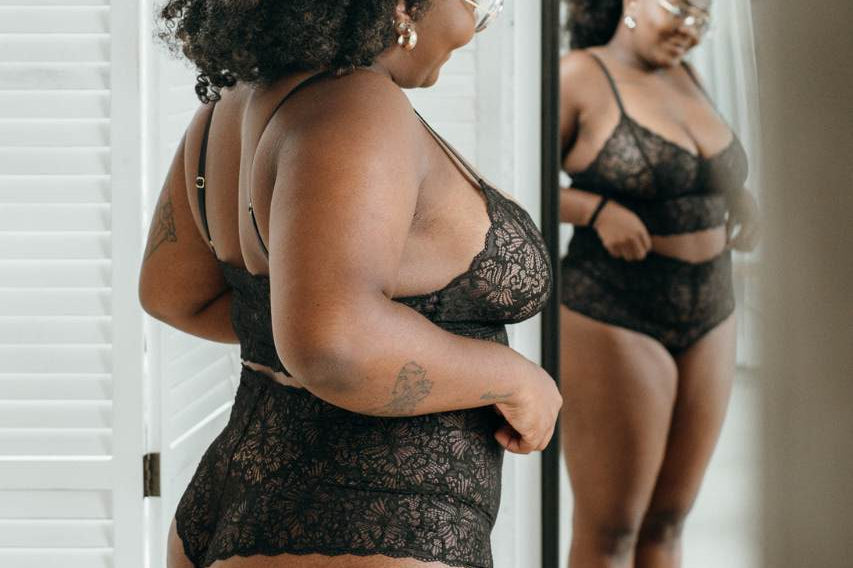 Woman in sustainable lace underwear in black looks at herself in the mirror