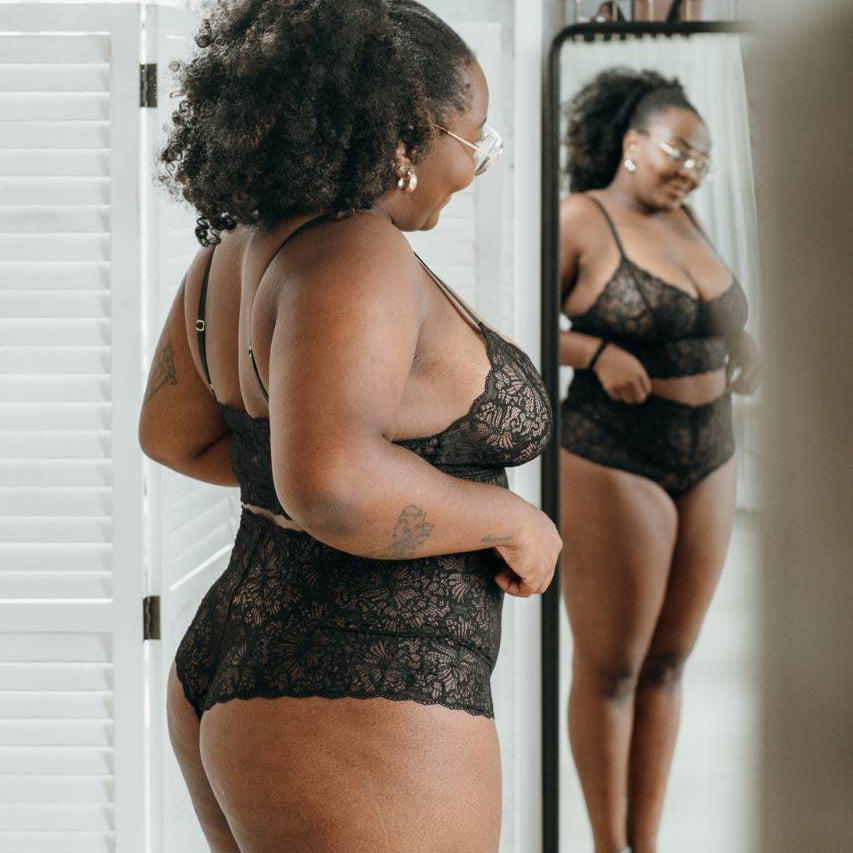 Donna in biancheria intima di pizzo sostenibile in nero si guarda allo specchio