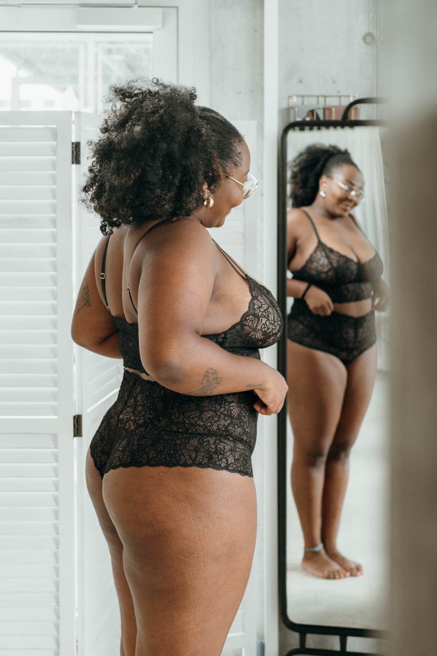Donna in biancheria intima di pizzo sostenibile in nero si guarda allo specchio