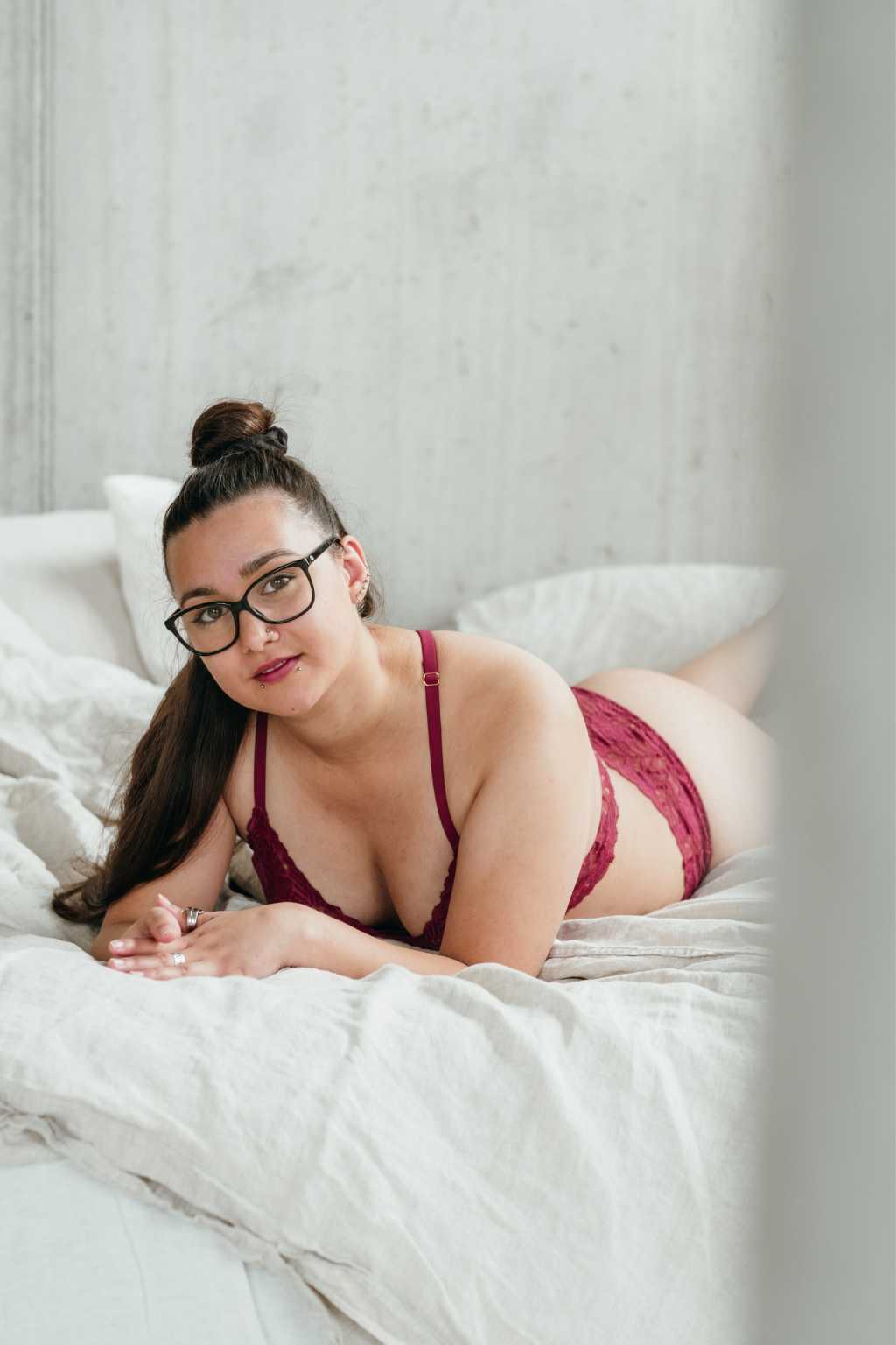Self-love boudoir shoot - woman in bed wears red underwear and matching lipstick