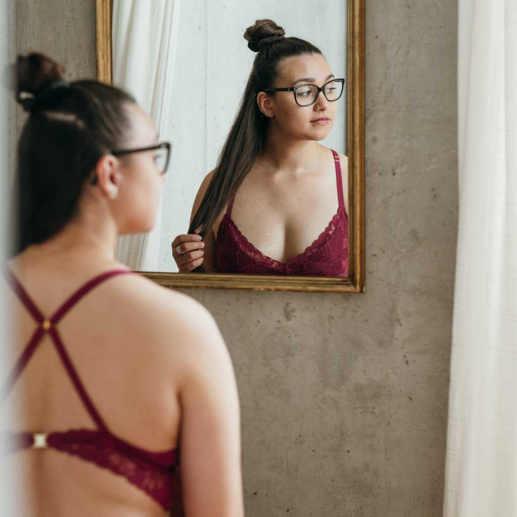 Boudoir Shooting - Woman wears red lace underwear and looks in the mirror