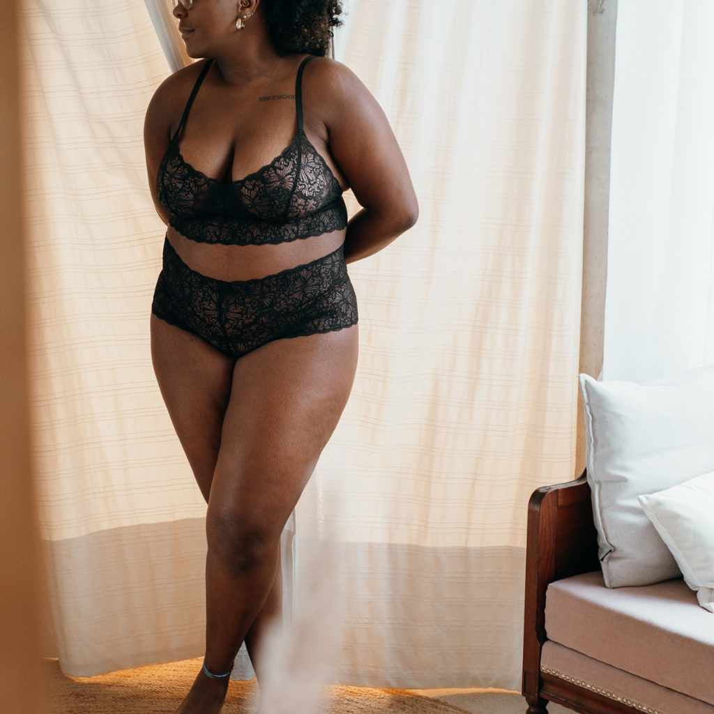 Model steps out of changing room in black lingerie.