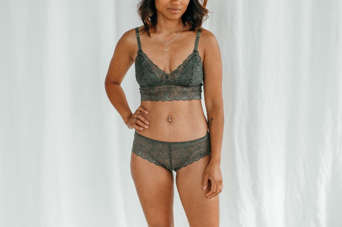 Model trägt Vivi Bralette mit herausnehmbaren Pads und passenden Slip aus dunkelgrüner Spitze.