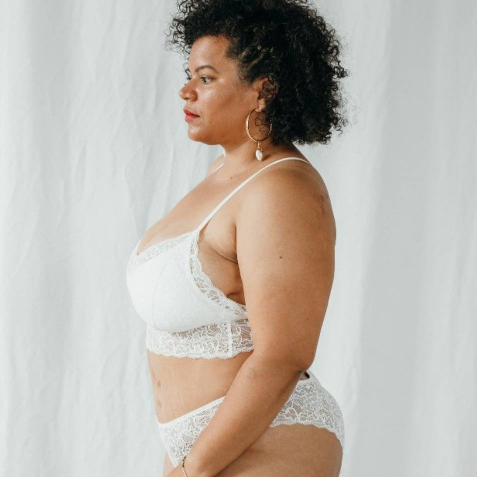 Model with black curls wears Bralette Vivi in size 85 G-H in white. 
