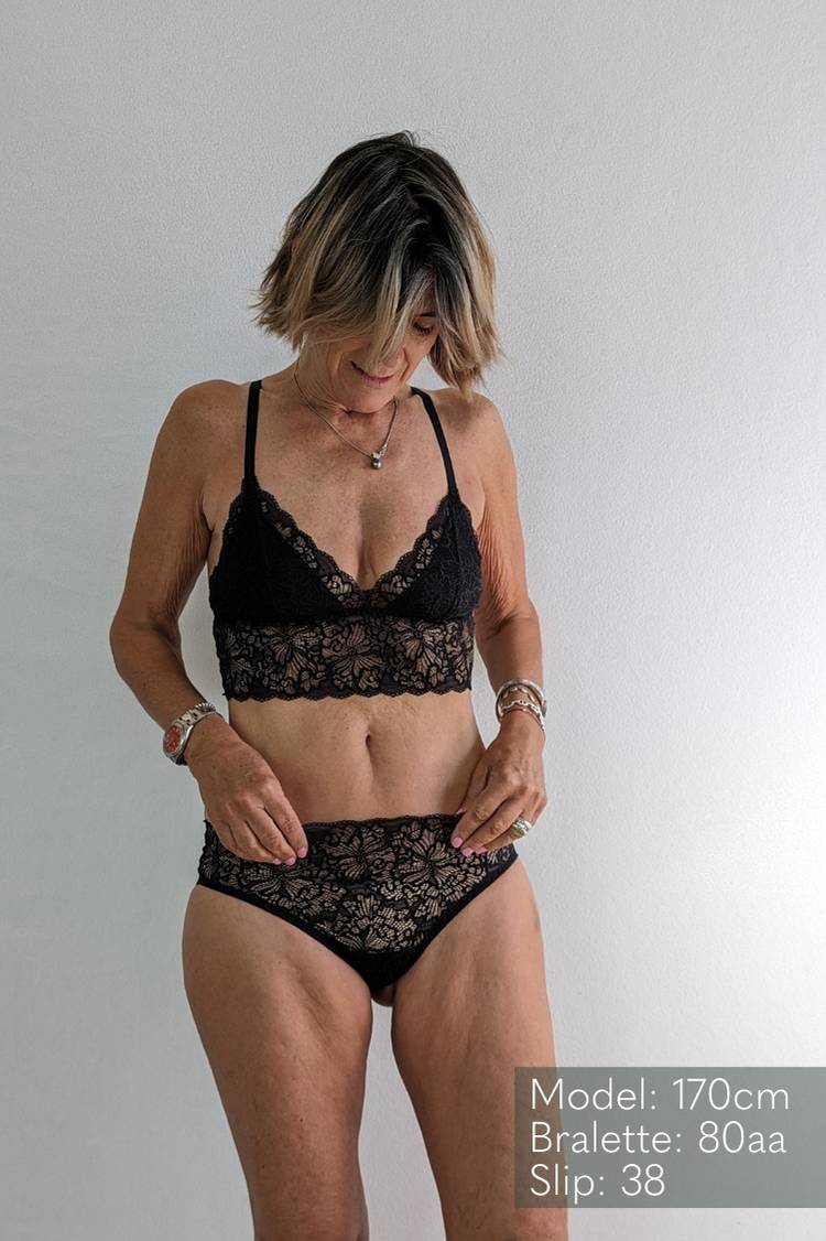 Model wears Bralette and slip made of black lace with a romantic pattern.
