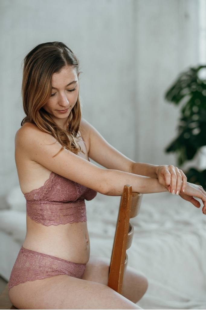 Woman sitting upside down on chair wearing rose lace lingerie.