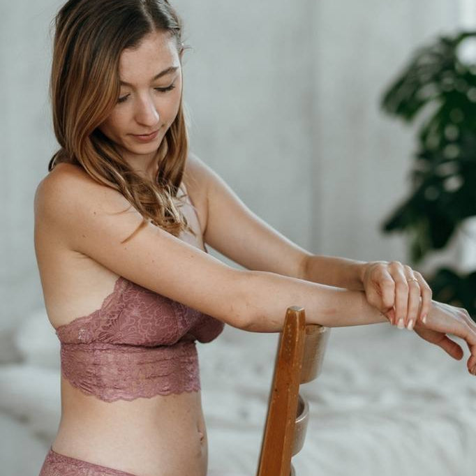 Woman sitting upside down on chair wearing rose lace lingerie.