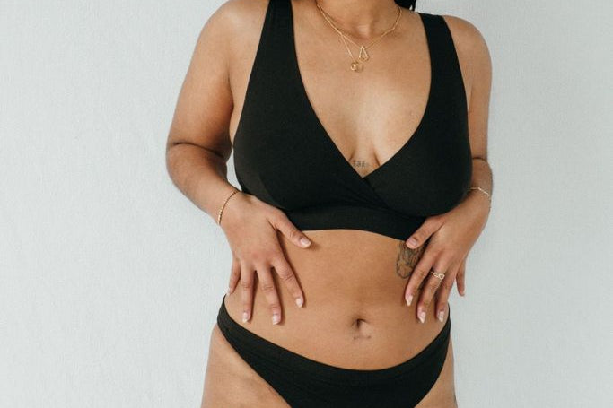Stehende Frau trägt schwatzen Slip und Bralette aus Lyocell tencel