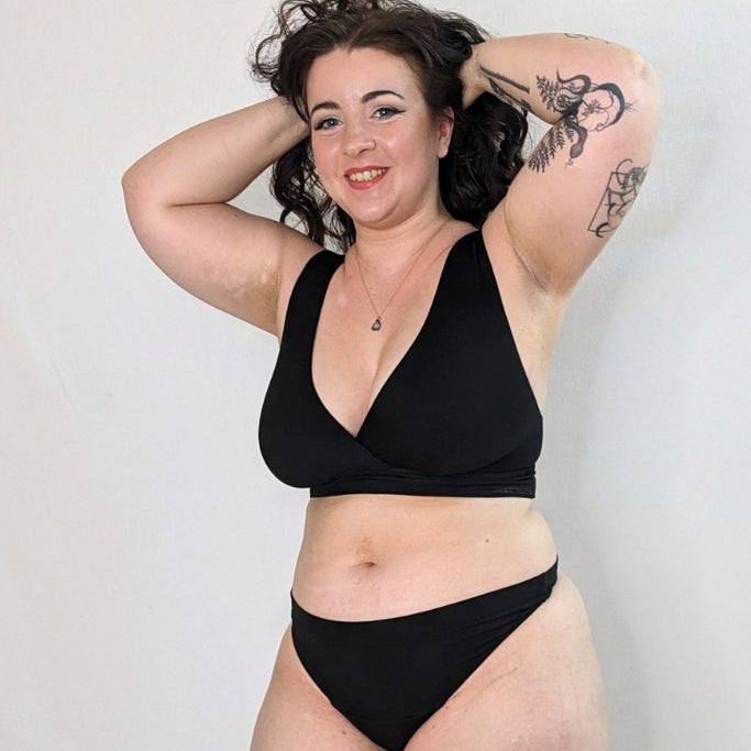 The woman wears black lingerie made of a String and a Bralette made of comfortable and skin-friendly fabric