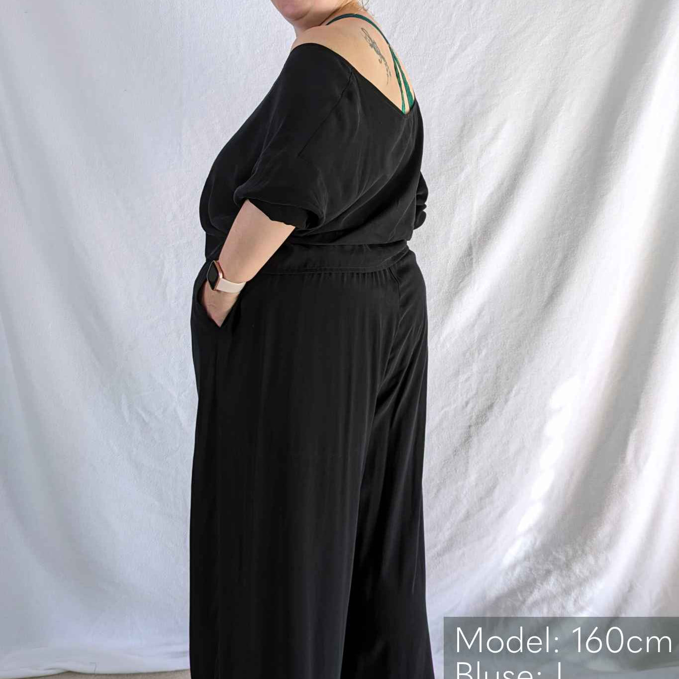 Woman looks cheekily over her shoulder in black pyjamas