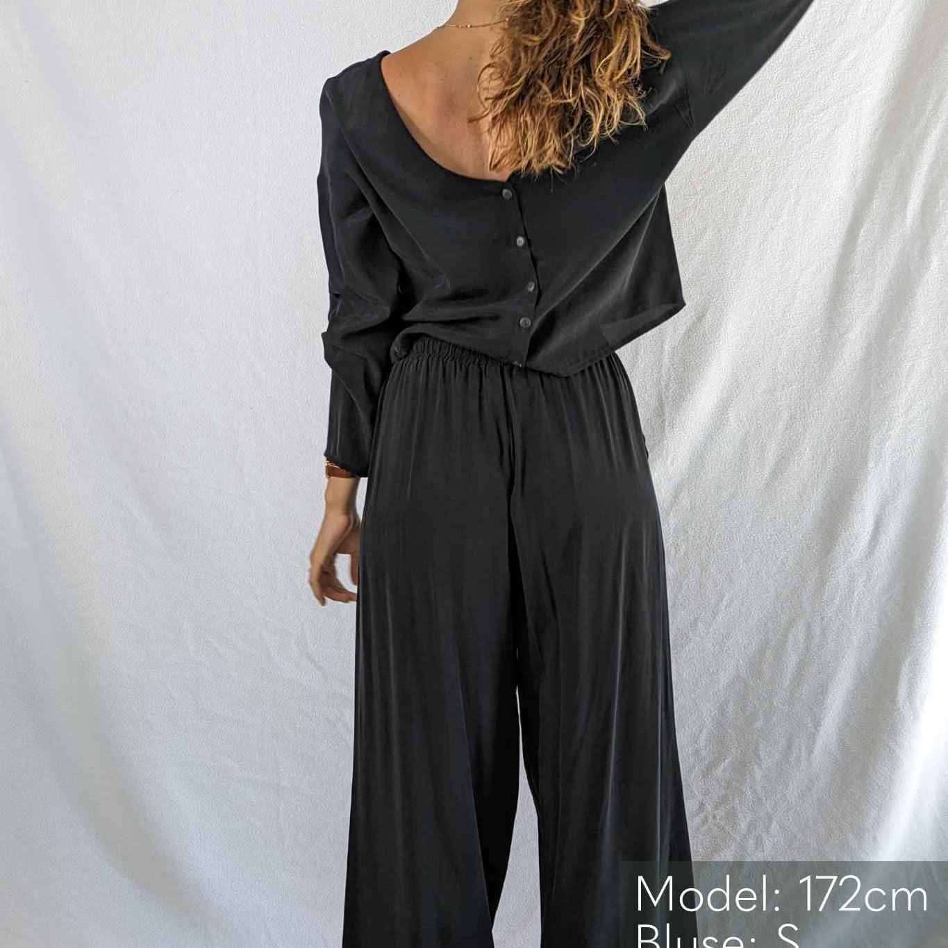 Woman shows the large back neckline of the Coco blouse