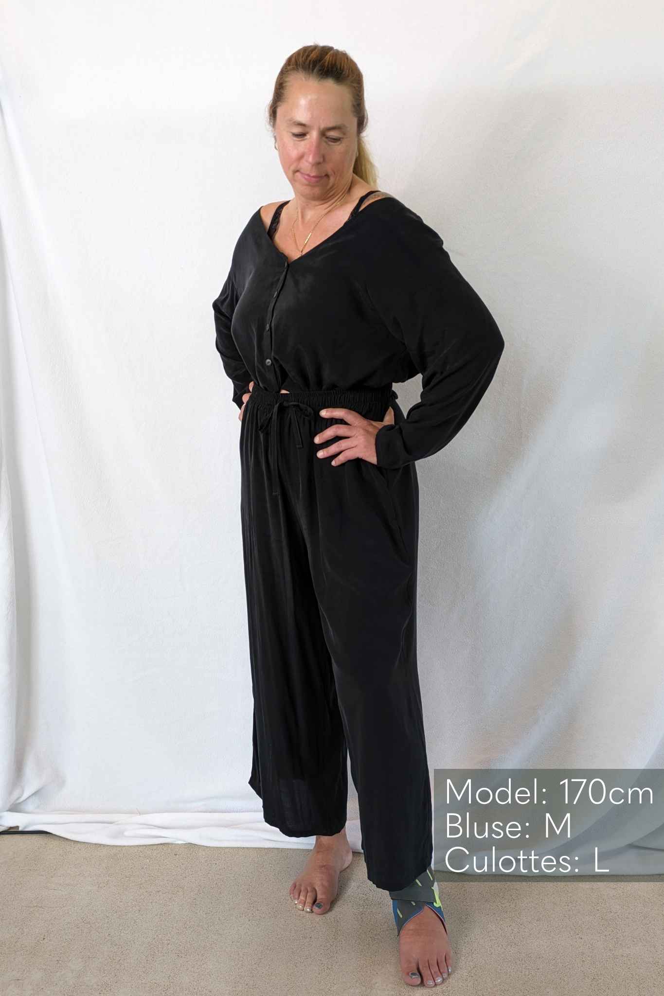 Woman wearing black pyjamas against a white background.