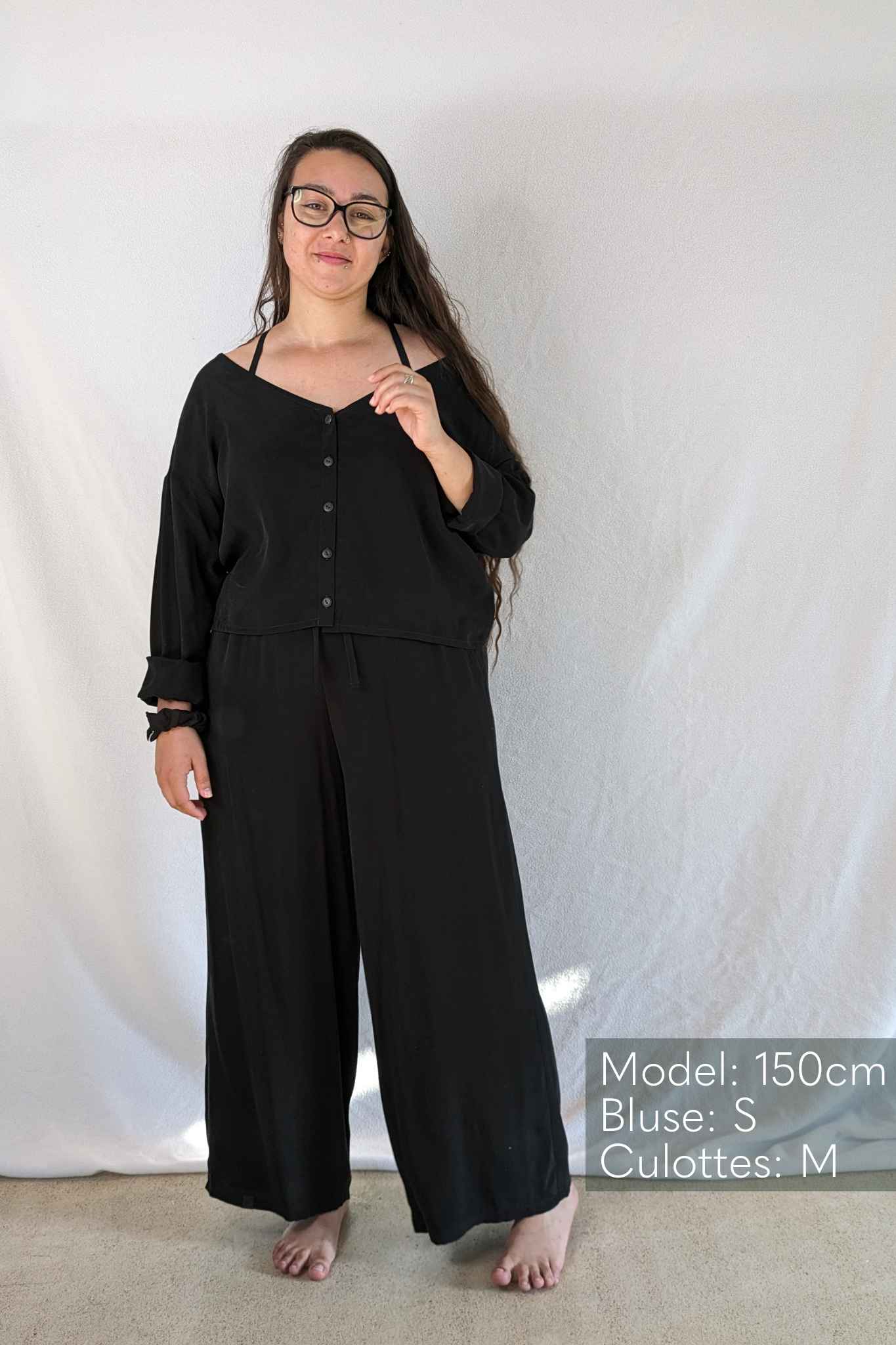 Woman with long hair wears the Coco pyjamas in black.