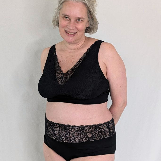 Grauhaariges Model trägt ein Bralette aus Lyocell Tencel mit wunderschöne Spitze drüber und dazu ein Höschen in schwarz