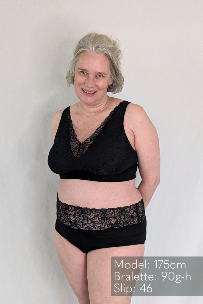 Grauhaariges Model trägt ein Bralette aus Lyocell Tencel mit wunderschöne Spitze drüber und dazu ein Höschen in schwarz