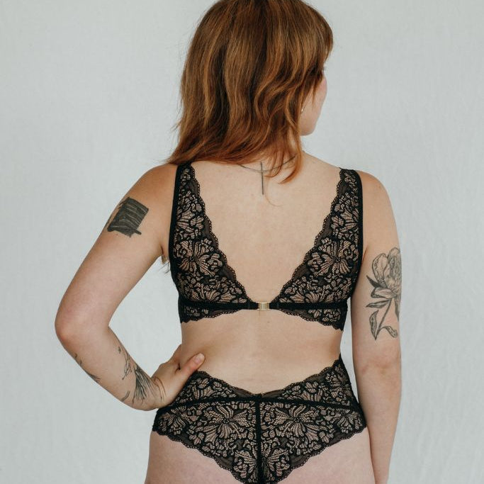 das Model zeigt sich von hinten in wunderschönem Dessous, welches hinten einen goldenen Verschluss hat.