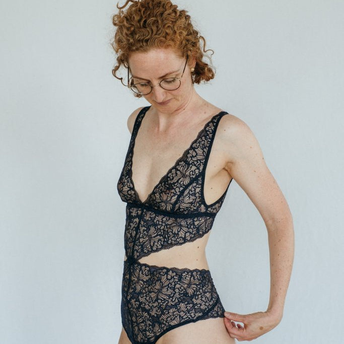 das Model mit den Locken trägt wunderschöne Unterwäsche in nacht blau aus recycelter Spitze