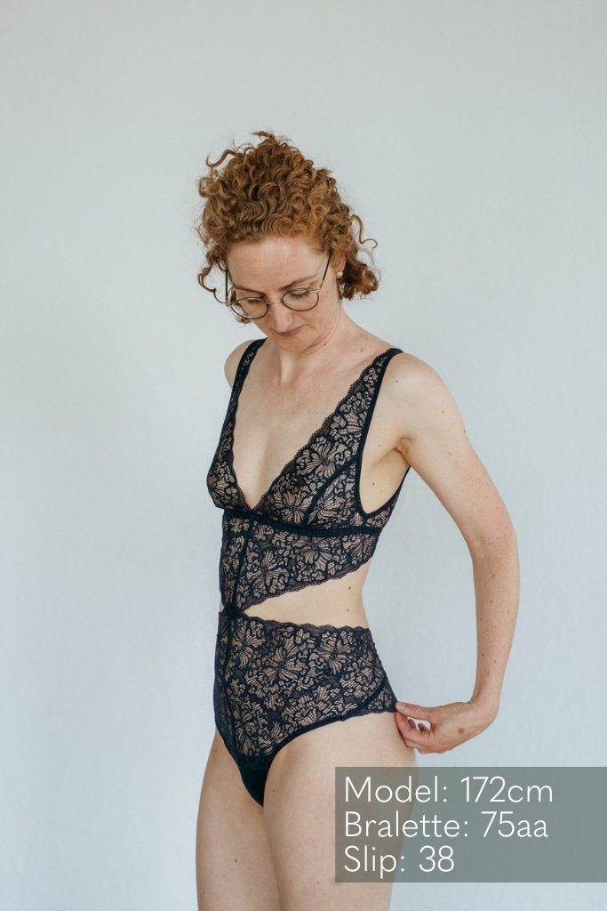 das Model mit den Locken trägt wunderschöne Unterwäsche in nacht blau aus recycelter Spitze
