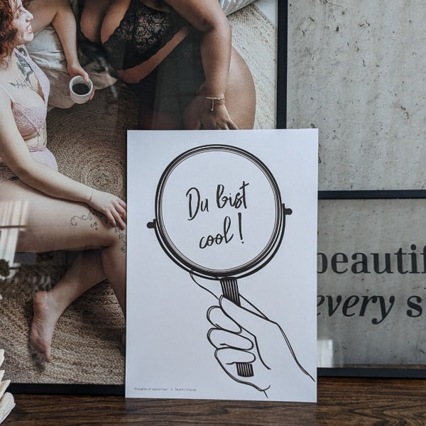 das Poster "du bist cool" vor einem Bild mit zwei Frauen in Unterwäsche