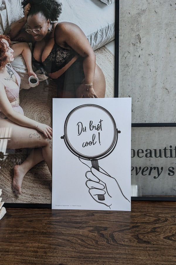das Poster "du bist cool" vor einem Bild mit zwei Frauen in Unterwäsche