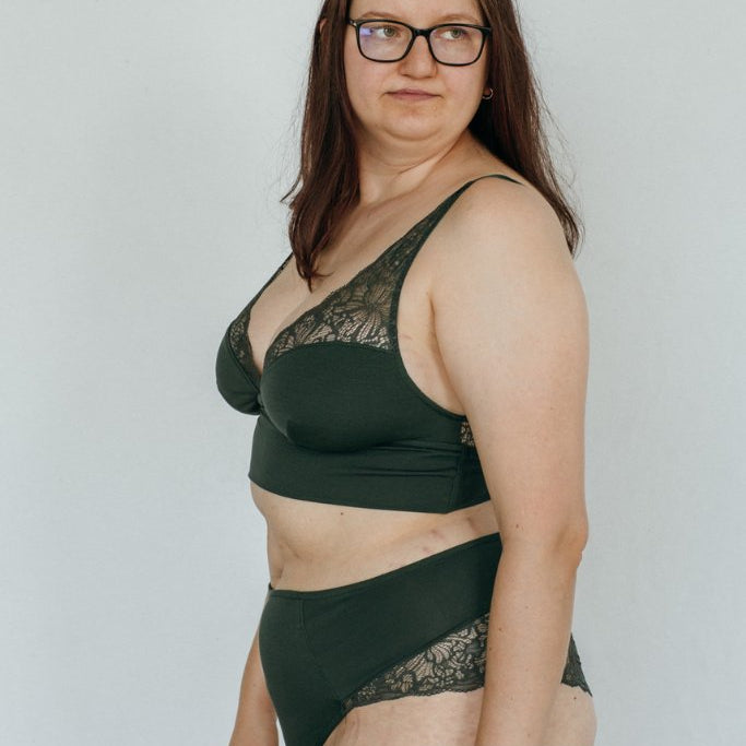 die Frau zeigt sich seitlich im Unterwäsche Set aus recycelter Spitze und Tencel Lyocell in jade grün