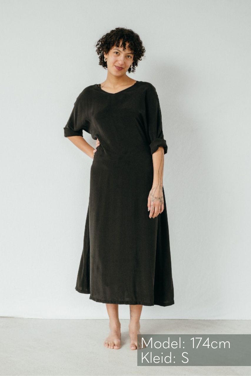 La modella indossa la vestaglia Kim di colore nero e appoggia la mano sul fianco.