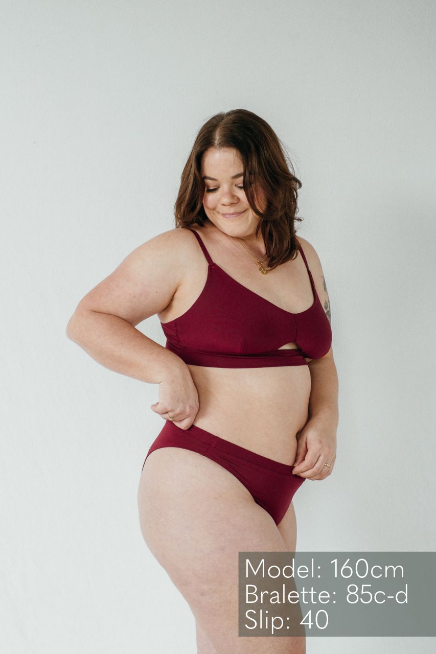 Das Model trägt das schöne Bralette und String Thea in der Farbe ruby red