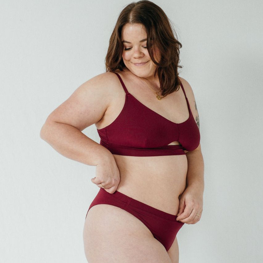 Das Model trägt das schöne Bralette und String Thea in der Farbe ruby red