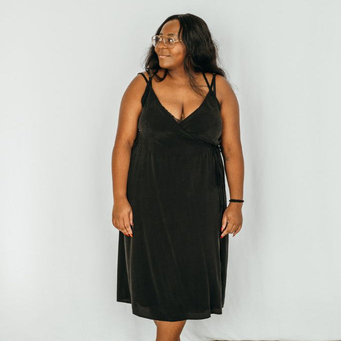 The model looks to the side and wears the Zia dress in black