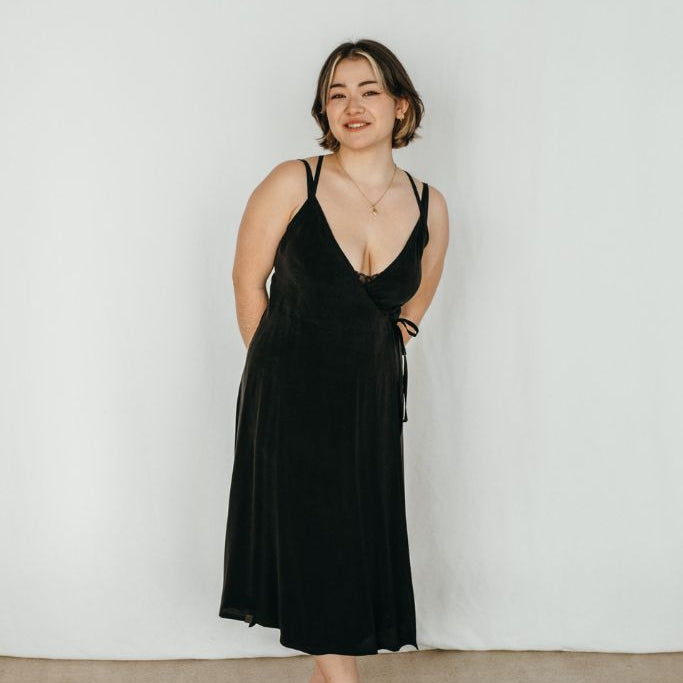 The woman wears the Zia slip dress in black
