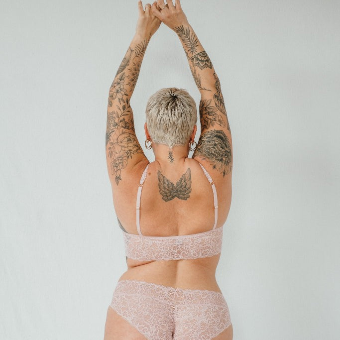 the woman shows her rear view and holds her hands in the air with the beautiful underwear 