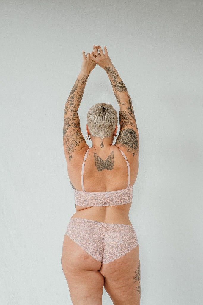 the woman shows her rear view and holds her hands in the air with the beautiful underwear 