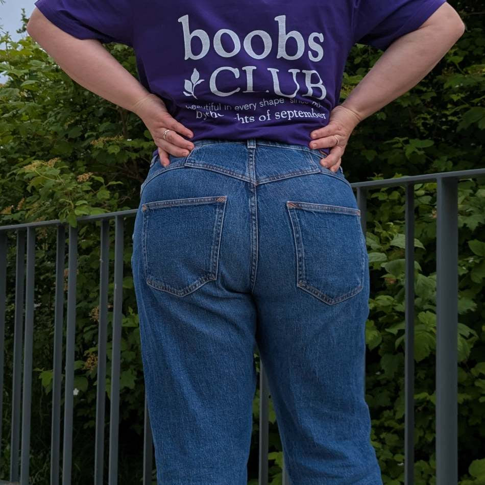 Foto zeigt Jess in unserem Boobs Club Shirt in violett von hinten mit dem Boobs Club Schriftzug.