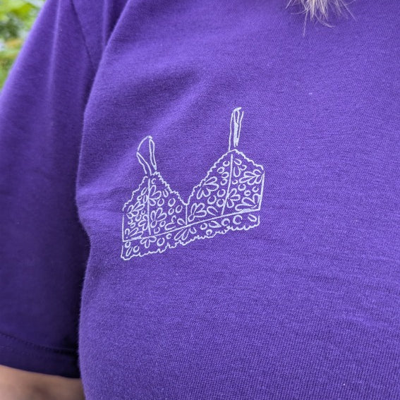 Foto zeigt eine Detailaufnahme von unserem Boobs Club Shirt in violett mit dem Bralette Print auf der Vorderseite.